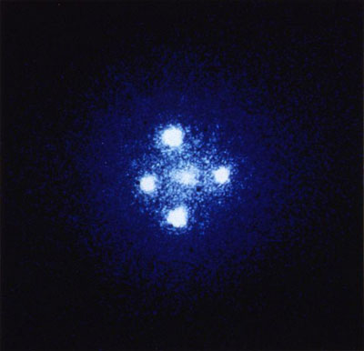 Figure 9 : Croix d'Einstein (QSO 2237+0305). L’observation de ce quasar situé à 8 milliards d’années-lumière se fait par déflexion à travers une galaxie-lentille située 20 fois moins loin, à 400 millions d’années-lumière (Photographie ESA, prise par le télescope américain Hubble).