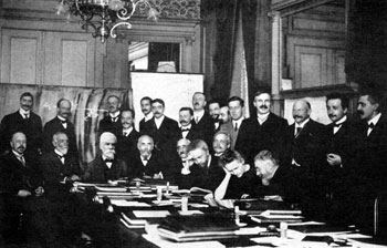 Figure 2 : Sur cette photo du congrès Solvay de 1911 apparaissent les deux principales figures de la physique pré-relativiste : Lorentz (quatrième assis à partir de la gauche) et Poincaré (assis au premier plan et discutant avec Marie Curie). Einstein et Langevin sont debout à droite. Lieu : hôtel Métropole, Bruxelles ; photo Wikimedia Commons).