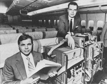 Figure 10 : Les physiciens américains Joseph Hafele et Richard Keating à bord d’un avion de ligne, avec leurs horloges atomiques au césium (revue Time Magazine, 18 octobre 1971)